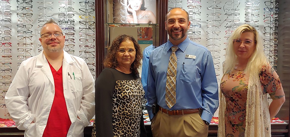 The Texas Midwest Optical team standing in front of the frame display wall